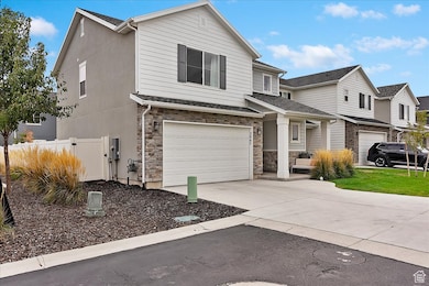 View of front facade with driveway, an attached garage, stone siding, stucco siding, and a residential view