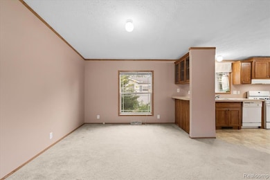 Kitchen featuring brown cabinetry, ornamental molding, glass insert cabinets, light colored carpet, and white appliances