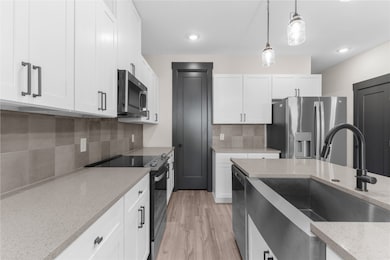 Kitchen featuring white cabinets, appliances with stainless steel finishes, light stone counters, and recessed lighting