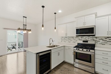 Kitchen with stainless steel appliances, white cabinetry, wine cooler, dark wood-style floors, and hanging light fixtures