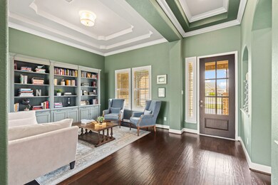 A look back at the welcoming Foyer with elevated double tray ceiling, crown molding, and streams of natural light filter through the leaded glass front door and shuttered sidelite.