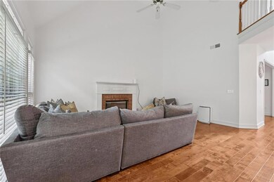 Living room with high vaulted ceiling, light wood finished floors, a ceiling fan, and a brick fireplace