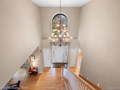 Foyer entrance with light wood-style floors, a chandelier, and a towering ceiling