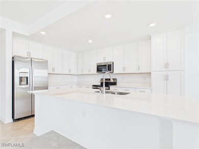 Kitchen featuring stainless steel appliances, white cabinets, light countertops, a large island, and recessed lighting