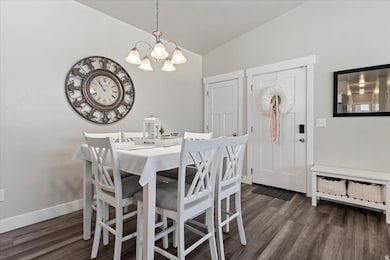 Dining room with vaulted ceiling, dark wood-type flooring, and a chandelier