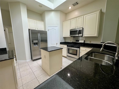 Kitchen featuring stainless steel appliances, light tile patterned floors, dark stone countertops, white cabinets, and recessed lighting
