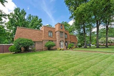 View of front of house featuring brick siding, a front yard, roof with shingles, and mansard roof