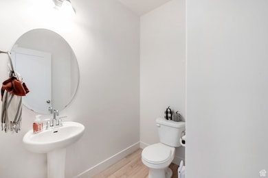 Half bathroom with toilet and wood finished floors