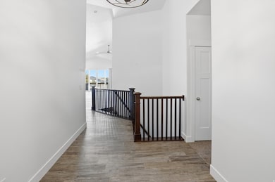 Corridor featuring an upstairs landing, light wood-style flooring, and a high ceiling