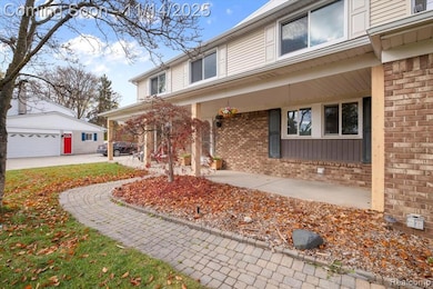 View of front of home with brick siding, covered porch, a garage, and an outdoor structure