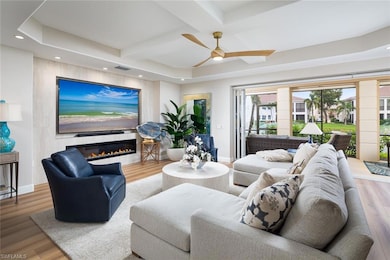 Living area featuring coffered ceiling, a glass covered fireplace, wood finished floors, recessed lighting, and a ceiling fan