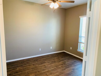 Empty room featuring dark wood-type flooring, ceiling fan, and a healthy amount of sunlight