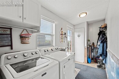 Laundry area with cabinet space, independent washer and dryer, a textured ceiling, and tile patterned flooring