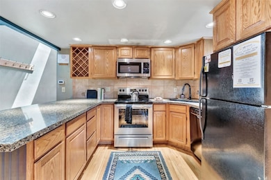 Kitchen with black appliances, a sink, a peninsula
