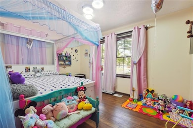 Bedroom with dark wood-style floors and a textured ceiling
