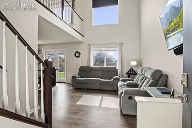 Living area with stairway, wood finished floors, a high ceiling, and french doors