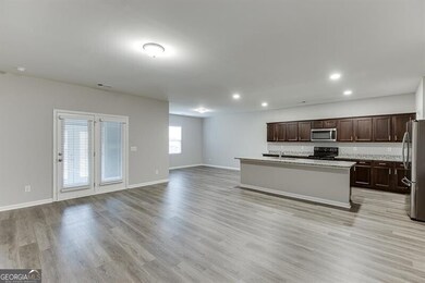 Kitchen featuring dark brown cabinetry, appliances with stainless steel finishes, light wood-type flooring, recessed lighting, and a kitchen island with sink
