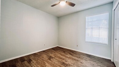 Unfurnished room featuring dark wood-style flooring, a textured ceiling, and a ceiling fan