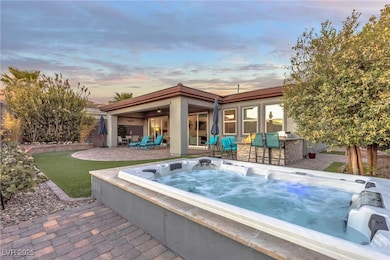 Pool at dusk with a patio area and an outdoor hot