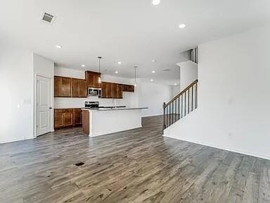Kitchen with open floor plan, pendant lighting, dark wood finished floors, recessed lighting, and a center island with sink