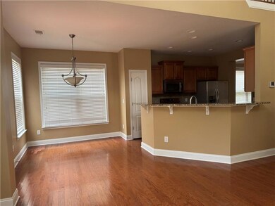 Kitchen featuring stainless steel appliances, a breakfast bar area, wood finished floors, brown cabinetry, and baseboards