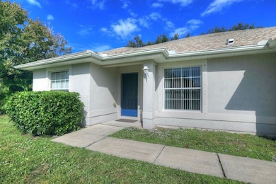 View of exterior entry with stucco siding and a lawn