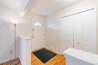 Entryway featuring light wood finished floors and beamed ceiling