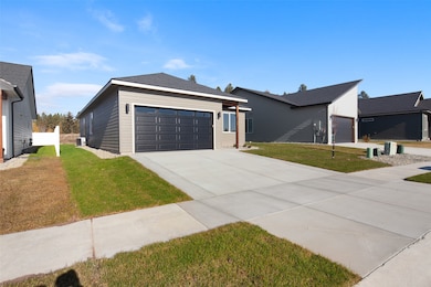 View of front facade with a front lawn, concrete driveway, and an attached garage