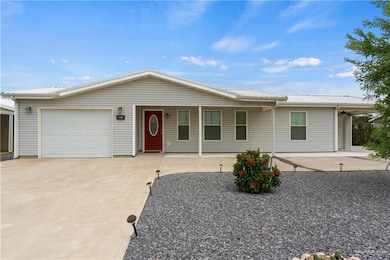 Ranch-style house with an attached garage, driveway, a metal roof, and a porch