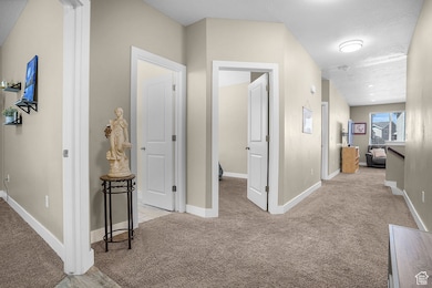 Hallway with baseboards and light colored carpet