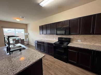 Kitchen featuring black appliances, tasteful back