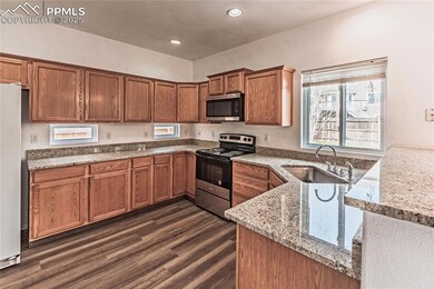 Kitchen with brown cabinets, light stone counters, a sink, and stainless steel appliances