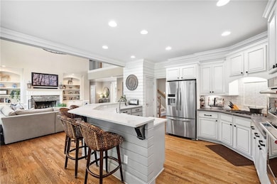 Kitchen with stainless steel appliances, ornamental molding, open floor plan, a breakfast bar, and a fireplace