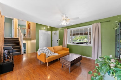 Living room featuring wood finished floors, stairway, and ceiling fan