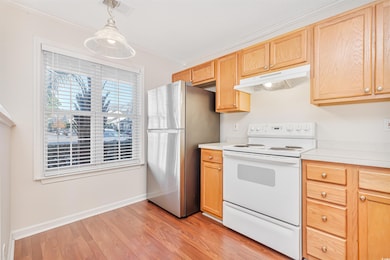Kitchen with stainless steel refrigerator, electric range, crown molding, decorative light fixtures, and light wood-type flooring