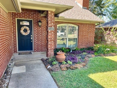 Doorway to property featuring a shingled roof, a chimney, brick siding, and a yard