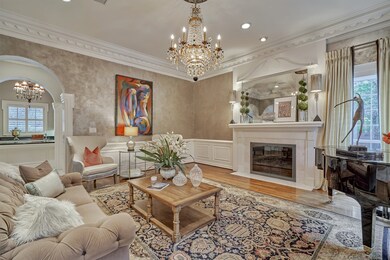 The formal living room features extensive trim and millwork, warm hardwoods, a sparkling beaded chandelier and a glass front fireplace.