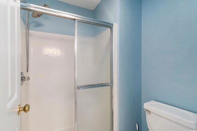 Full bath featuring a shower with door and toilet