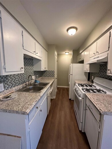 Kitchen featuring range hood, a sink, dark wood-s