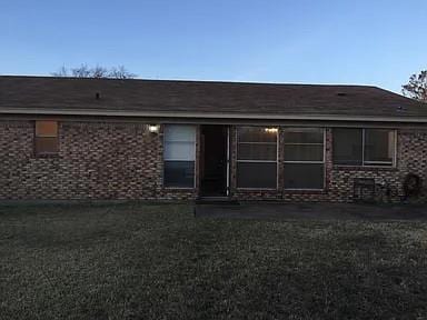 Back of house with brick siding and a lawn