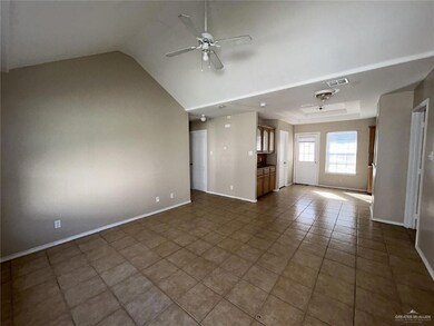 Unfurnished living room with ceiling fan, dark tile patterned flooring, and lofted ceiling