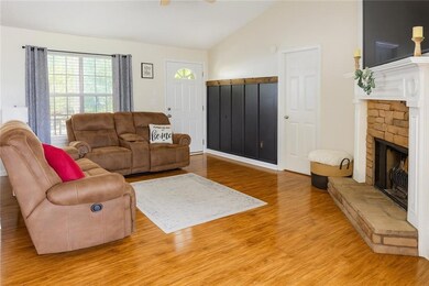 Living area featuring lofted ceiling, light wood-style flooring, a fireplace, and a ceiling fan