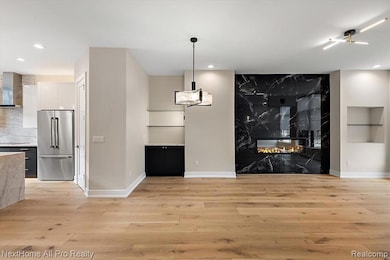 Unfurnished dining area with a premium fireplace, light wood finished floors, and recessed lighting