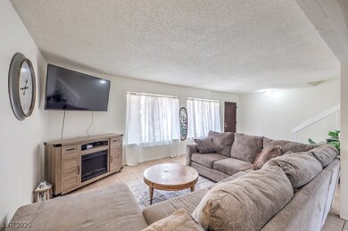 Living room with a textured ceiling, light tile pa