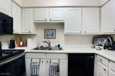 Kitchen with black appliances, white cabinets, and light countertops