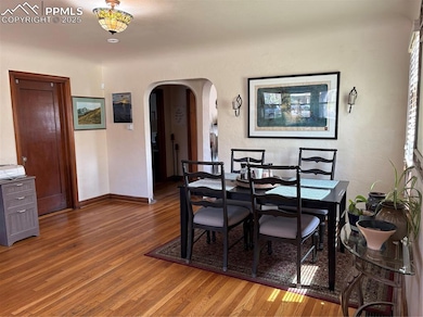 Dining area featuring wood finished floors, arched walkways, and a textured wall