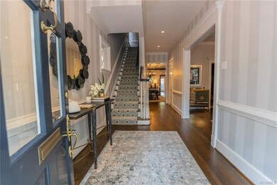 The grand entrance hall features staircase to upper level, beautiful hardwood floors and moldings, a large cased opening to the formal living room, coat closed, and powder bath.