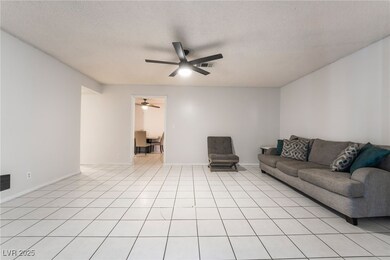 Living room with ceiling fan, a textured ceiling,