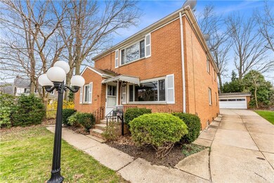 View of front facade featuring brick siding, a detached garage, and an outdoor structure