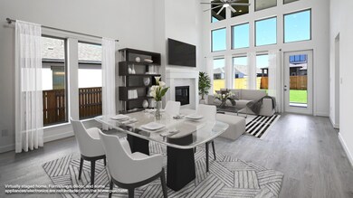 Dining area with a premium fireplace, wood finished floors, and a towering ceiling